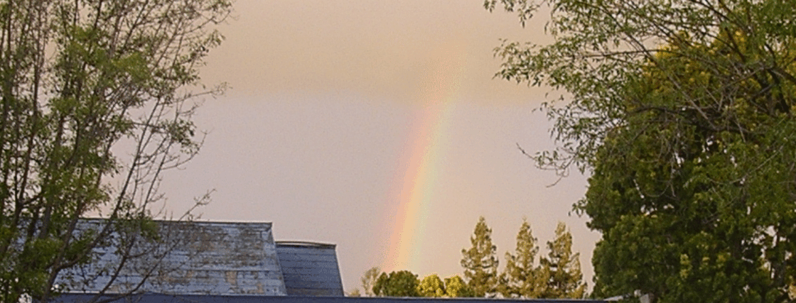 Rainbow above roof at sunset